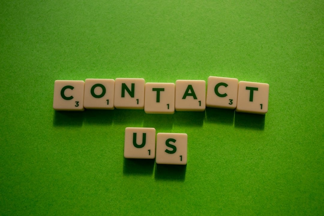 White letter tiles spell 'CONTACT US' on a green surface.