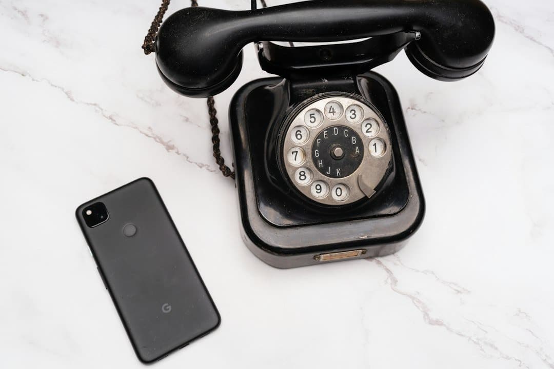 A vintage rotary phone beside a modern smartphone on marble.