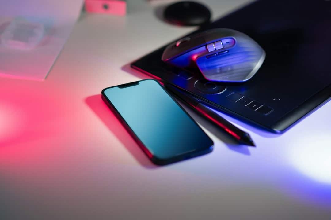 Smartphone, drawing tablet and mouse on light surface.