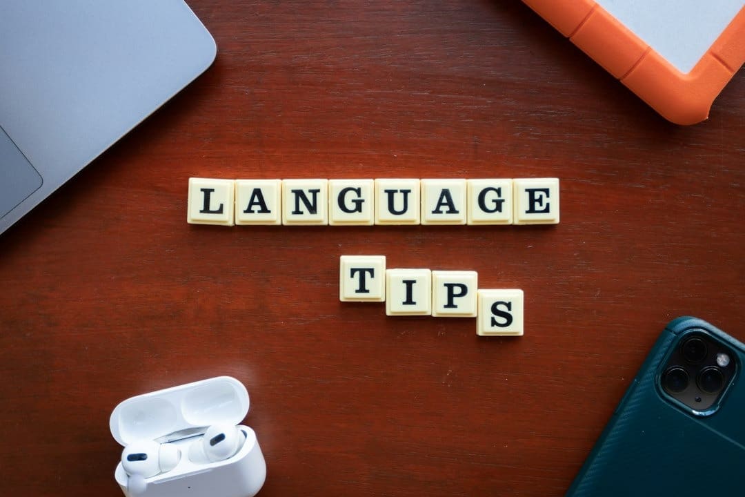 Scrabble tiles spelling 'LANGUAGE TIPS' on a wooden surface.